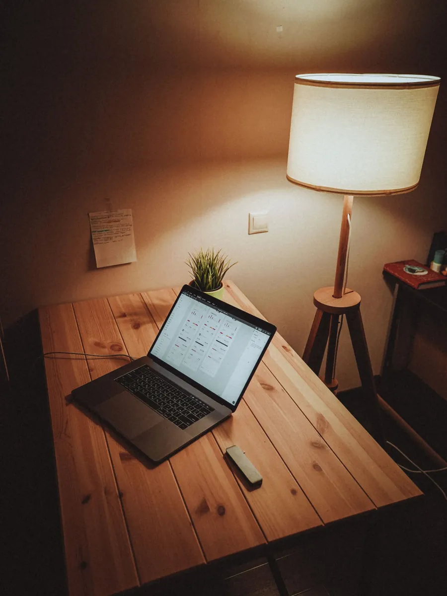 A warm lamp-lit desk with a laptop at the end of the day