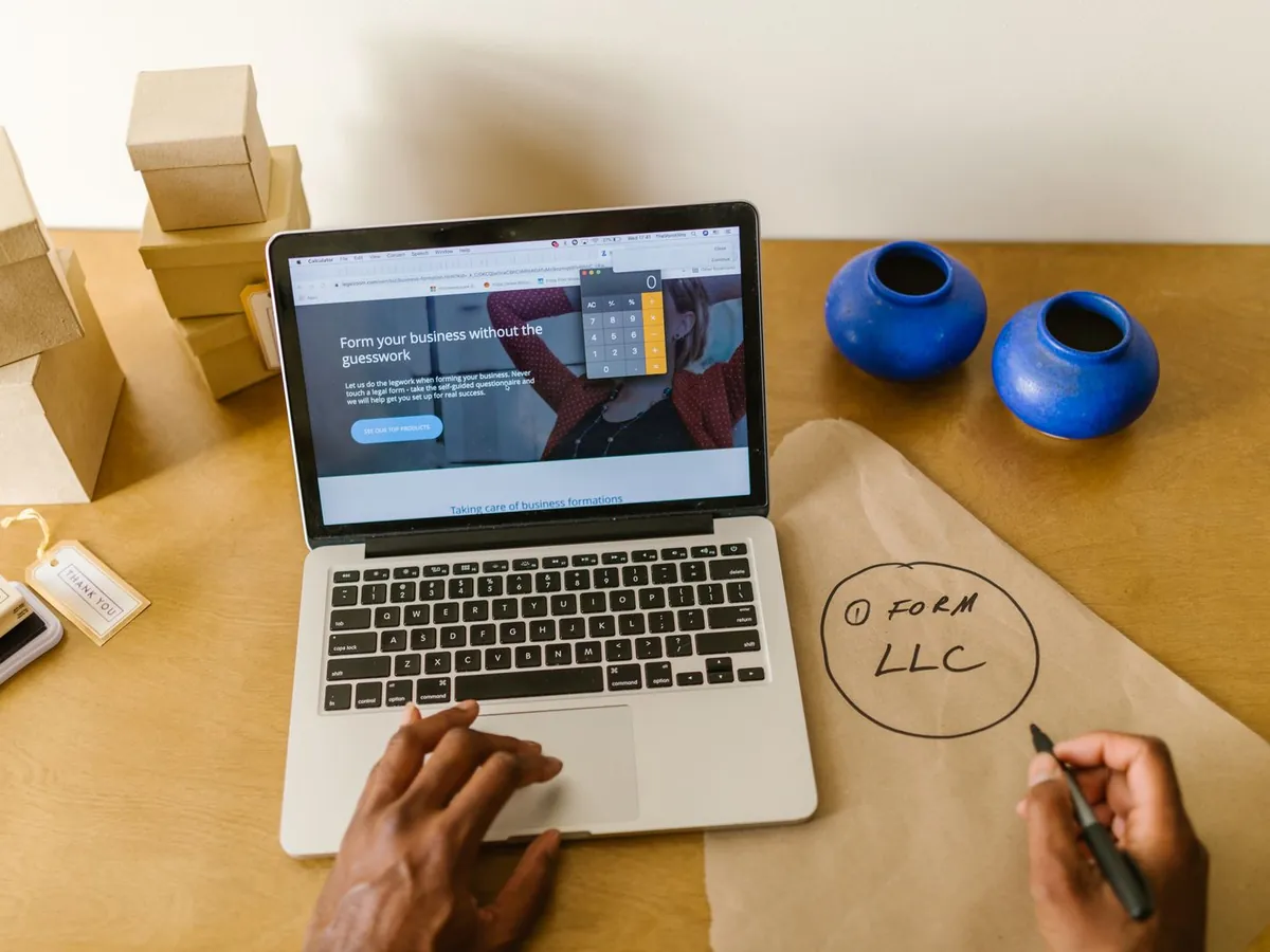 A laptop on a desk beside parcels and handwritten notes